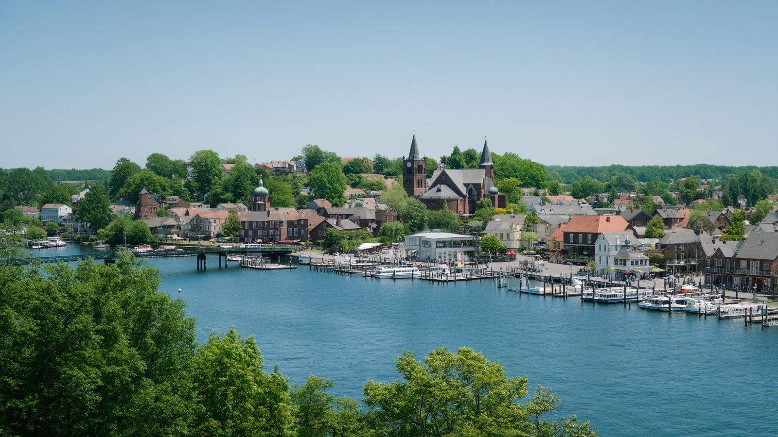 Historic river town with church steeples and a marina on a wide blue river