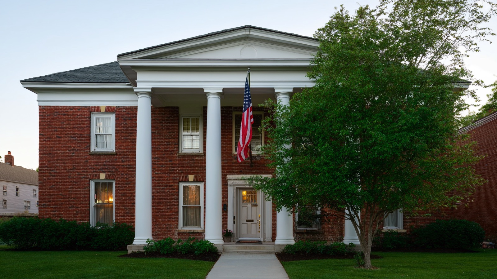Brick American home with white columns and a flag on the front porch